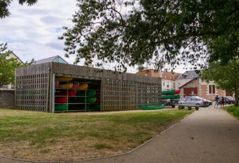 Photo d'une structure en bois où sont rangés des kayaks de différentes couleurs.