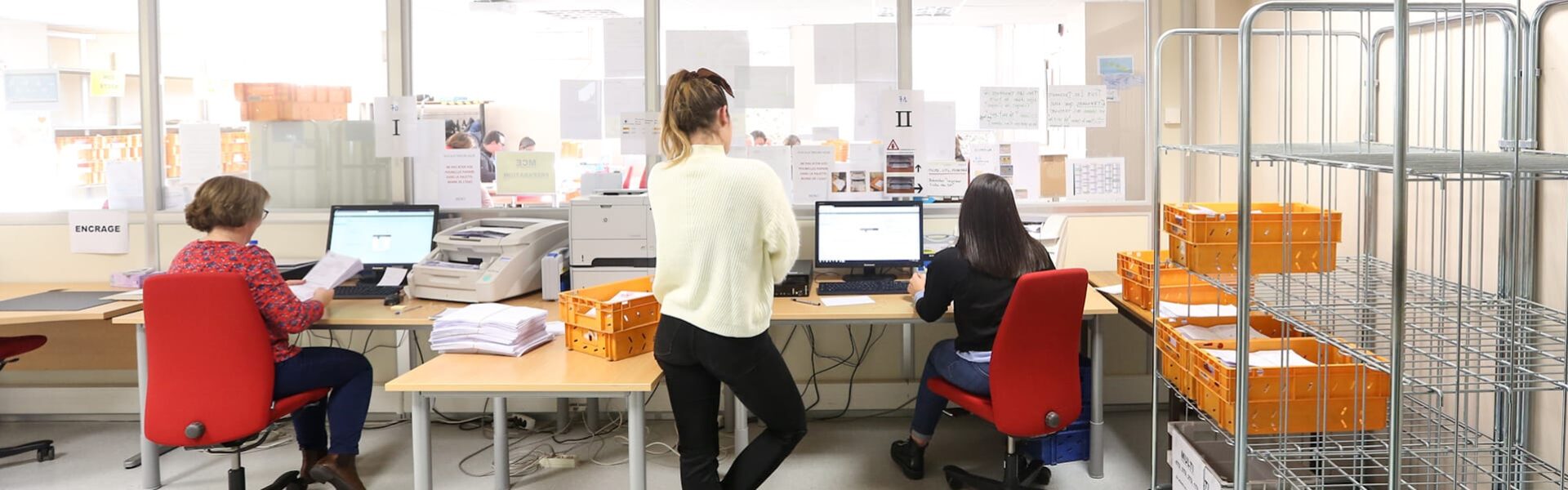 3 personnes de dos travaillant au service courrier d'une entreprise