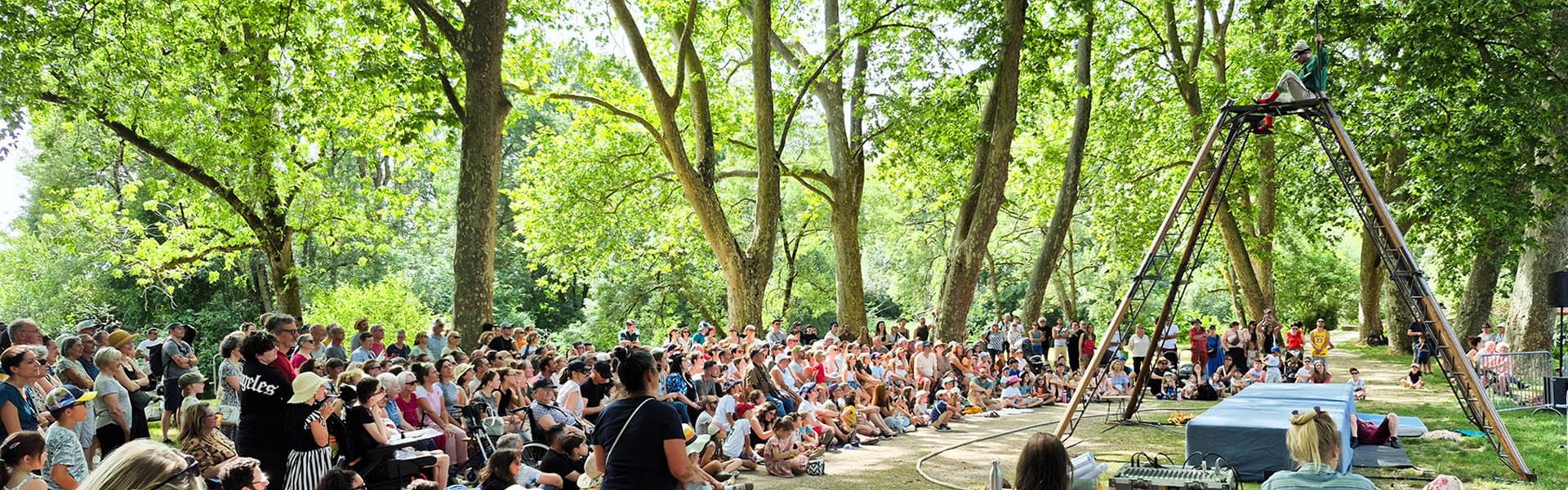 Une foule importante de spectateurs assise sous les arbres dans le cadre du festival O Val de l'Indre 2026