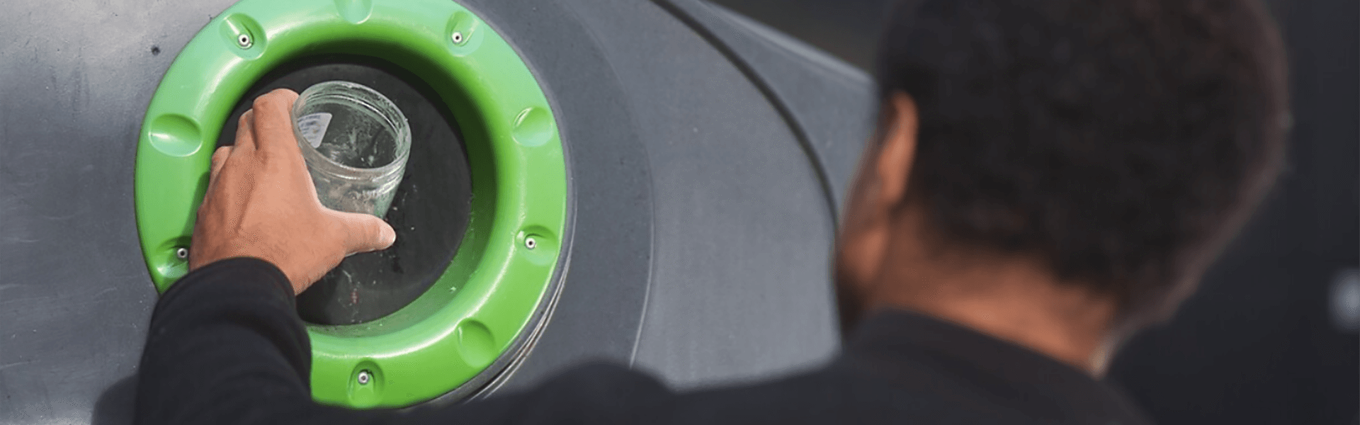 Homme déposant un bocal dans un point d'apport volontaire pour le verre